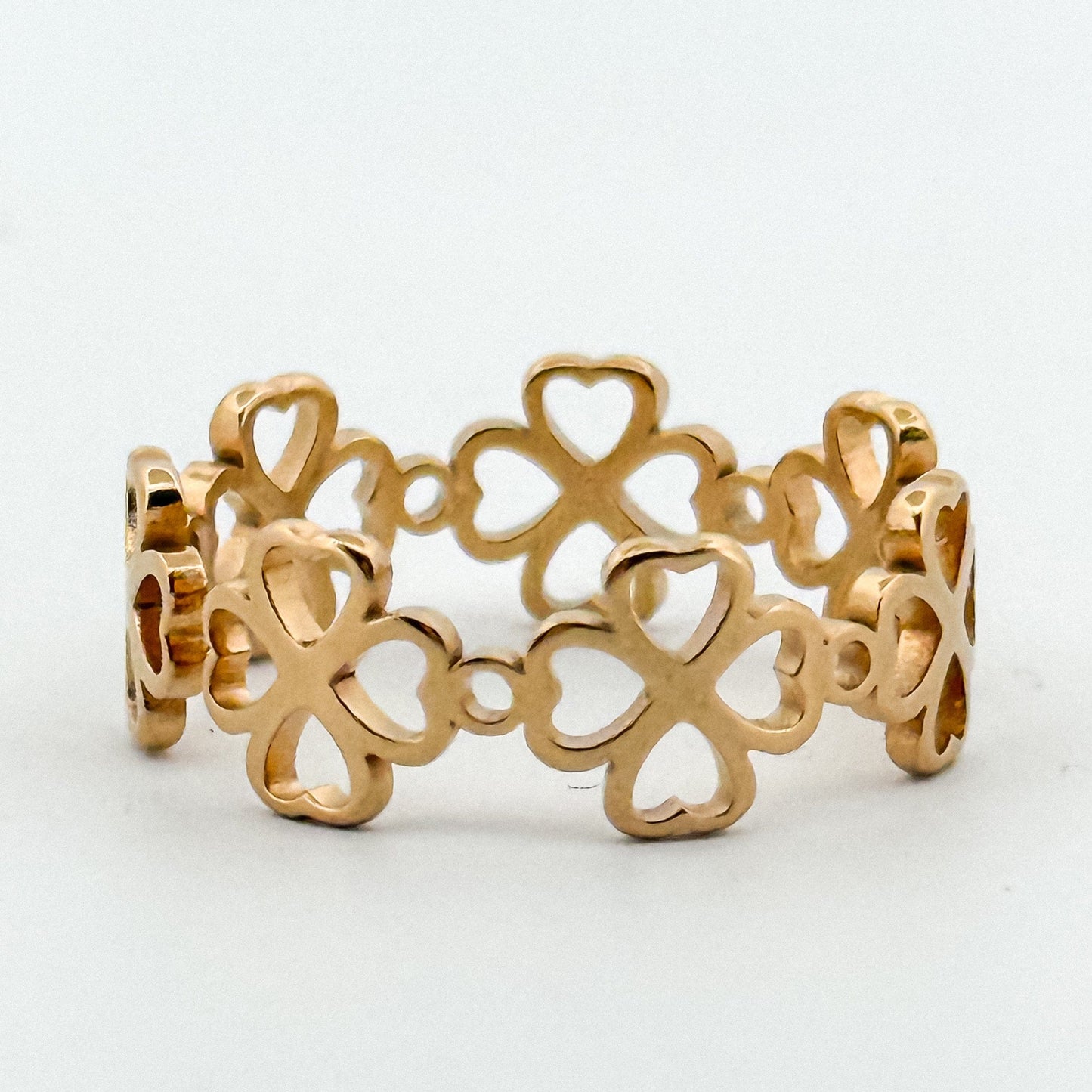 Gold ring with clover designs on a light gray background