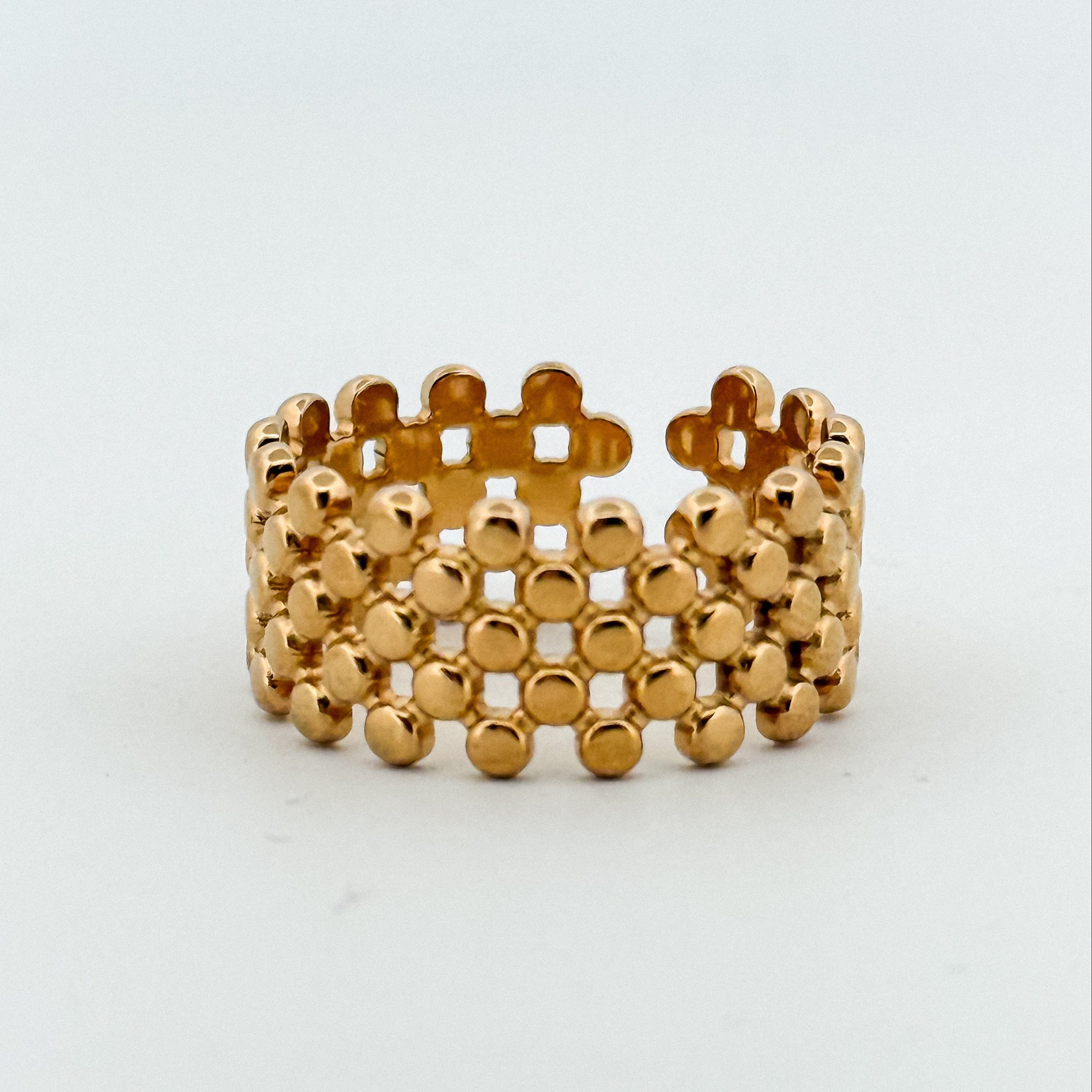 Gold ring with a textured design on a white background