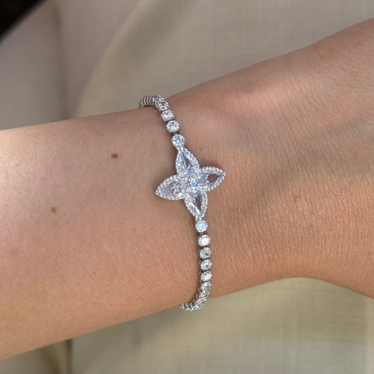 Silver bracelet with a flower-shaped charm on a wrist 