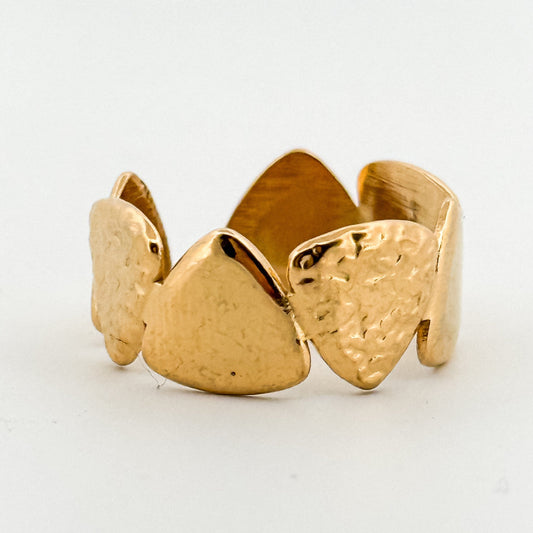 Gold ring with textured triangle designs on a white background