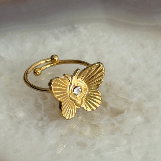 Gold butterfly ring with a diamond on a light stone background