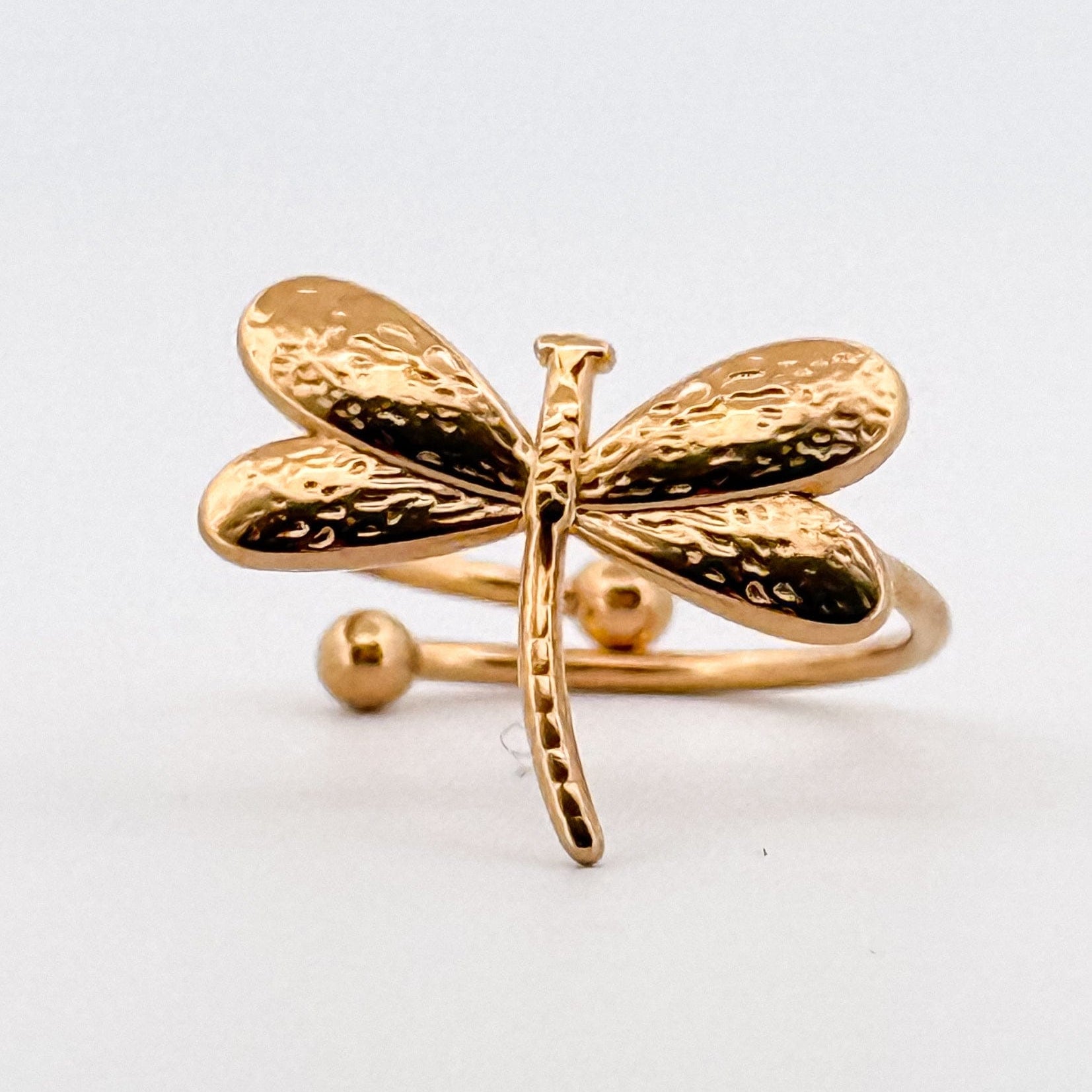 Gold dragonfly-shaped ring on a white background