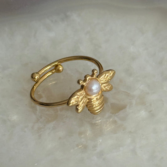 Gold ring with a pearl on a marble surface