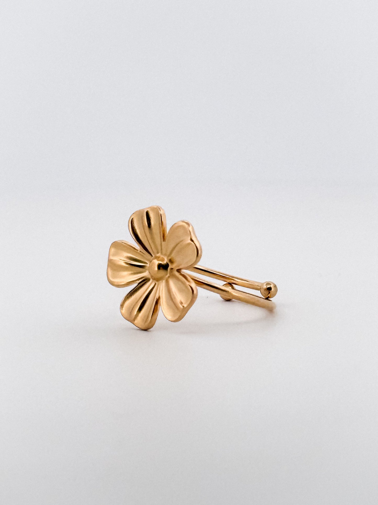 Gold flower-shaped ring on a light gray background