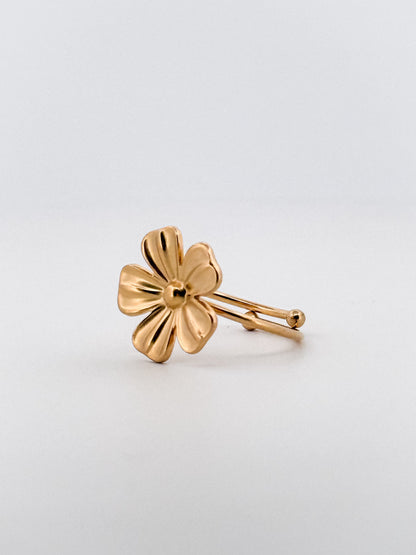 Gold flower-shaped ring on a light gray background
