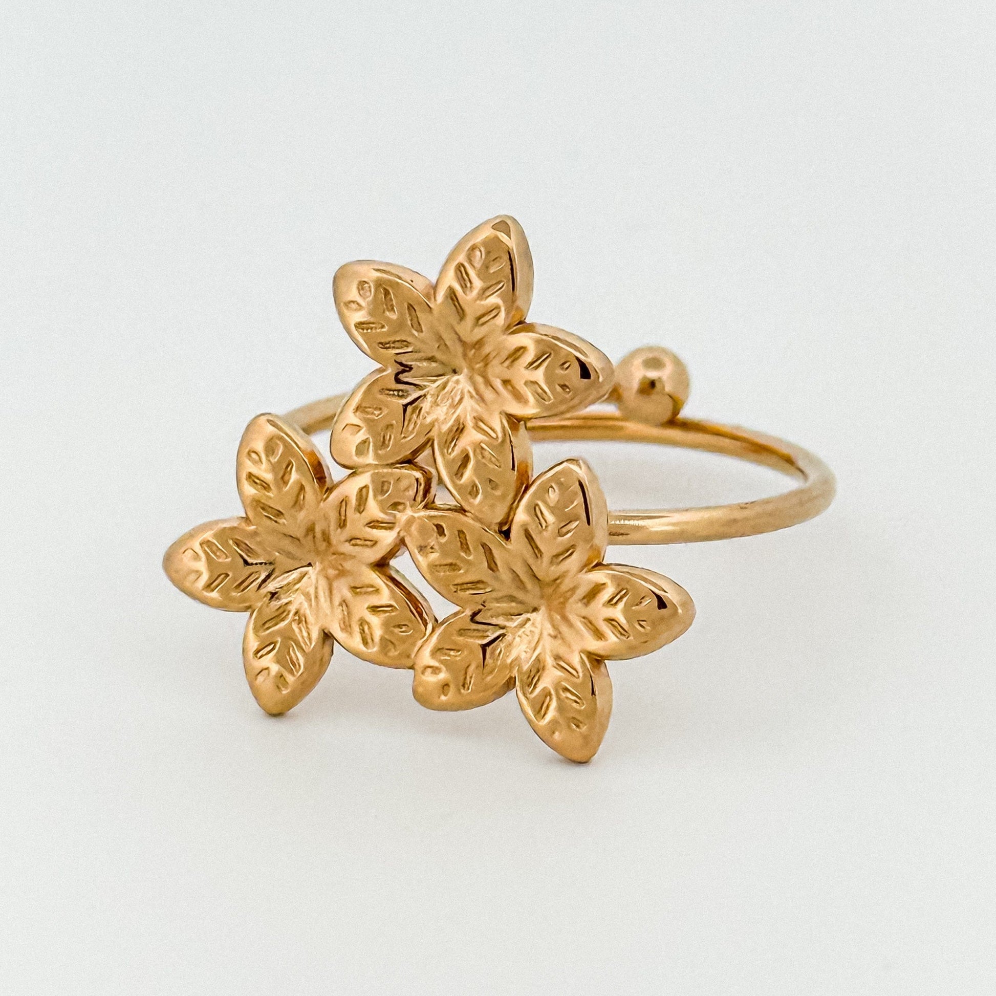 Gold flower-shaped ring on a light gray background