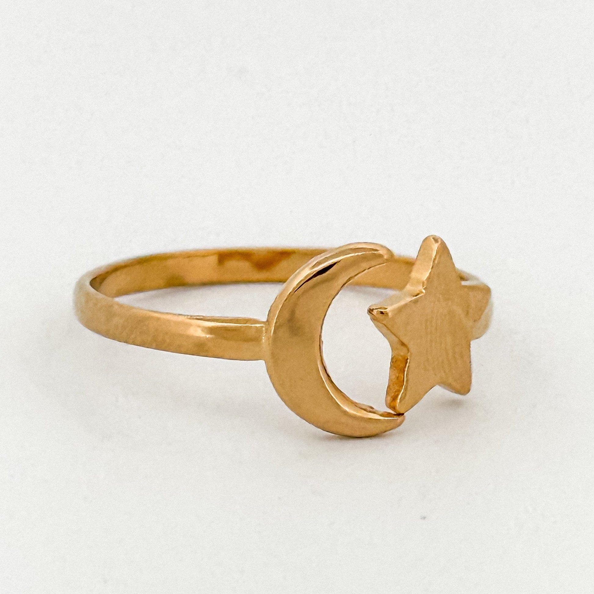 Gold ring with moon and star design on a white background