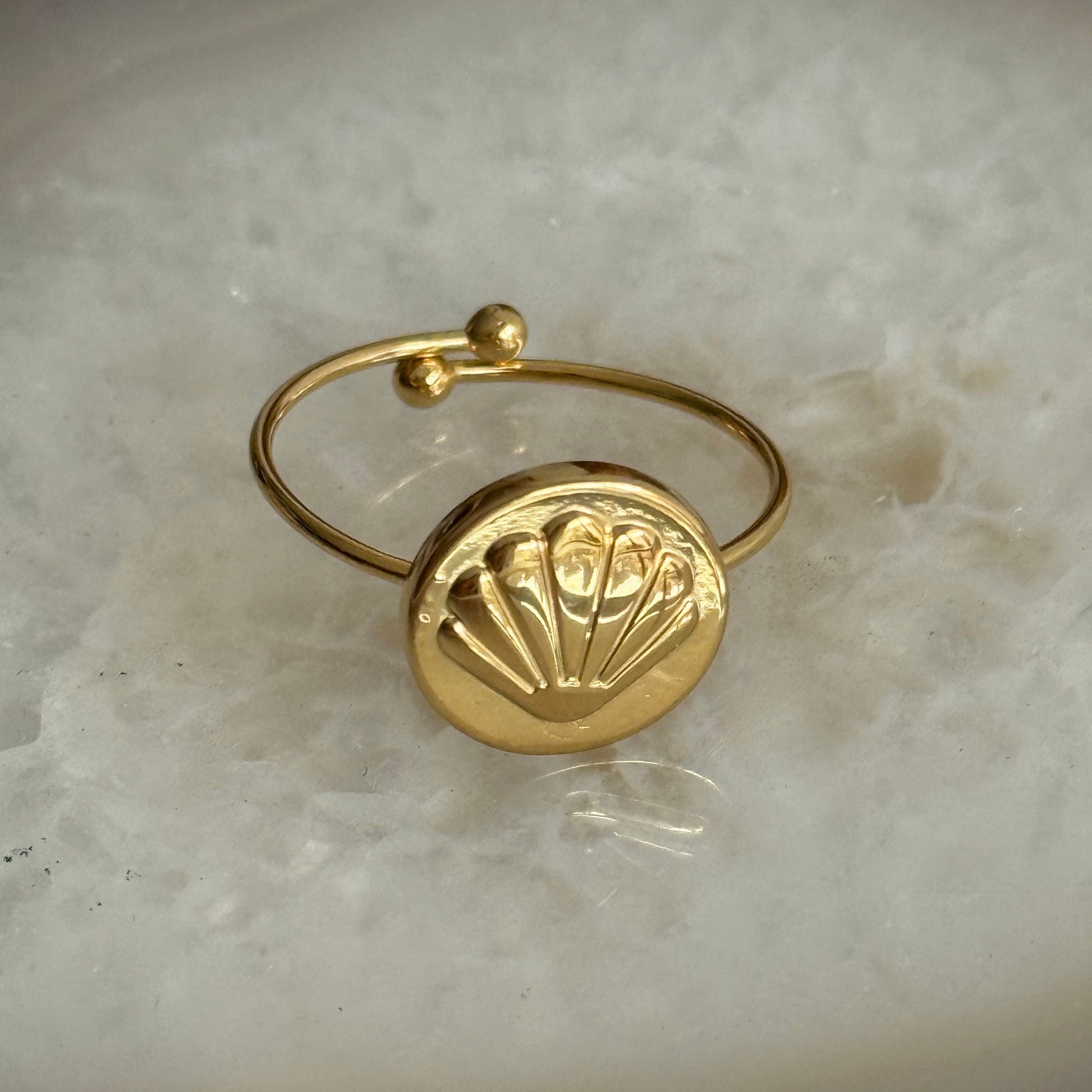 Gold ring with a decorative design on a marble surface