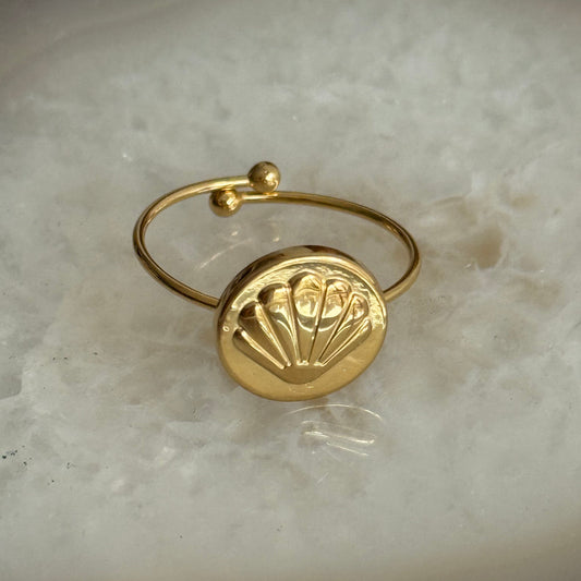 Gold ring with a decorative design on a marble surface