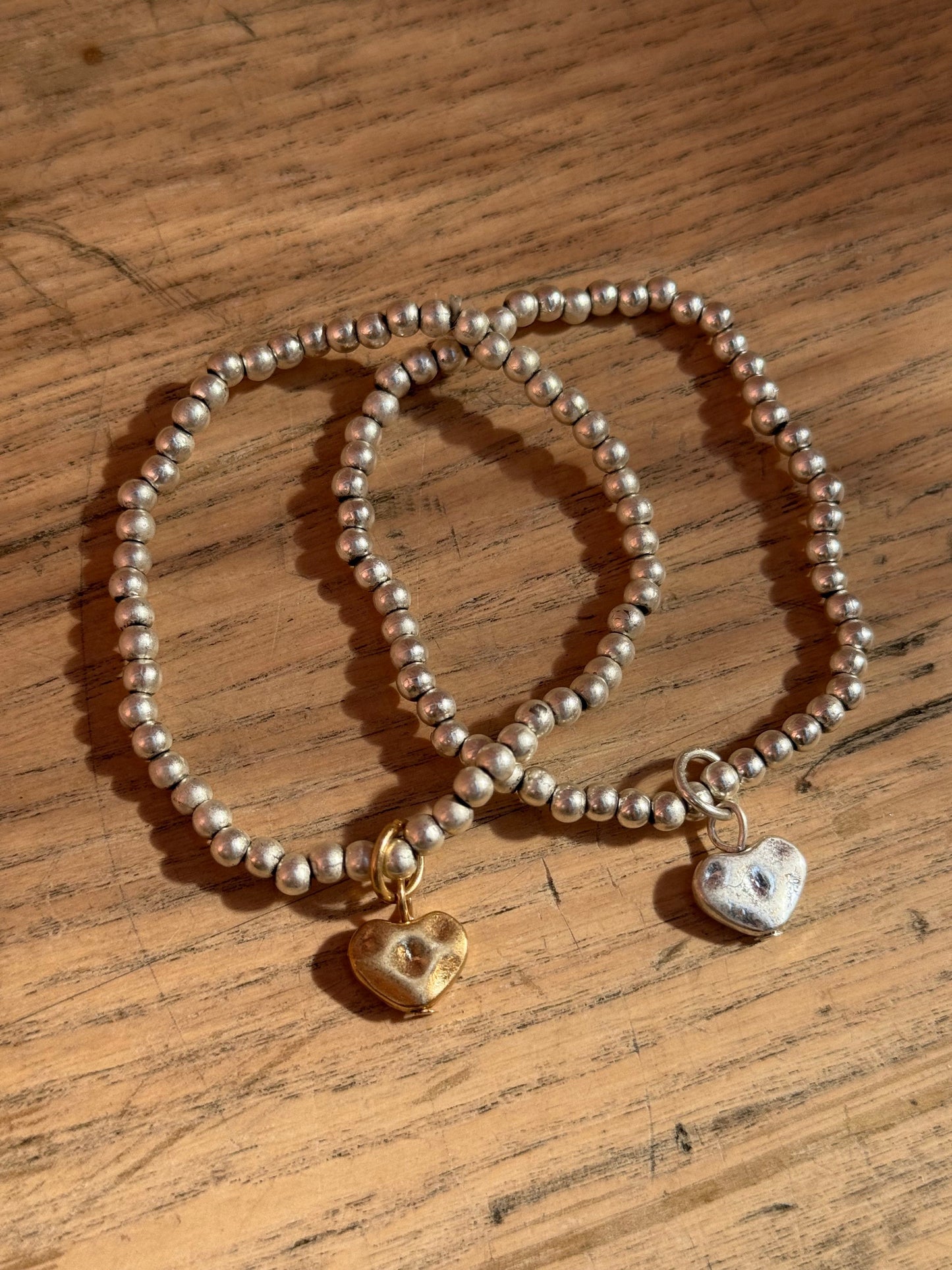 Set of two silver bracelets with heart charms in gold and silver