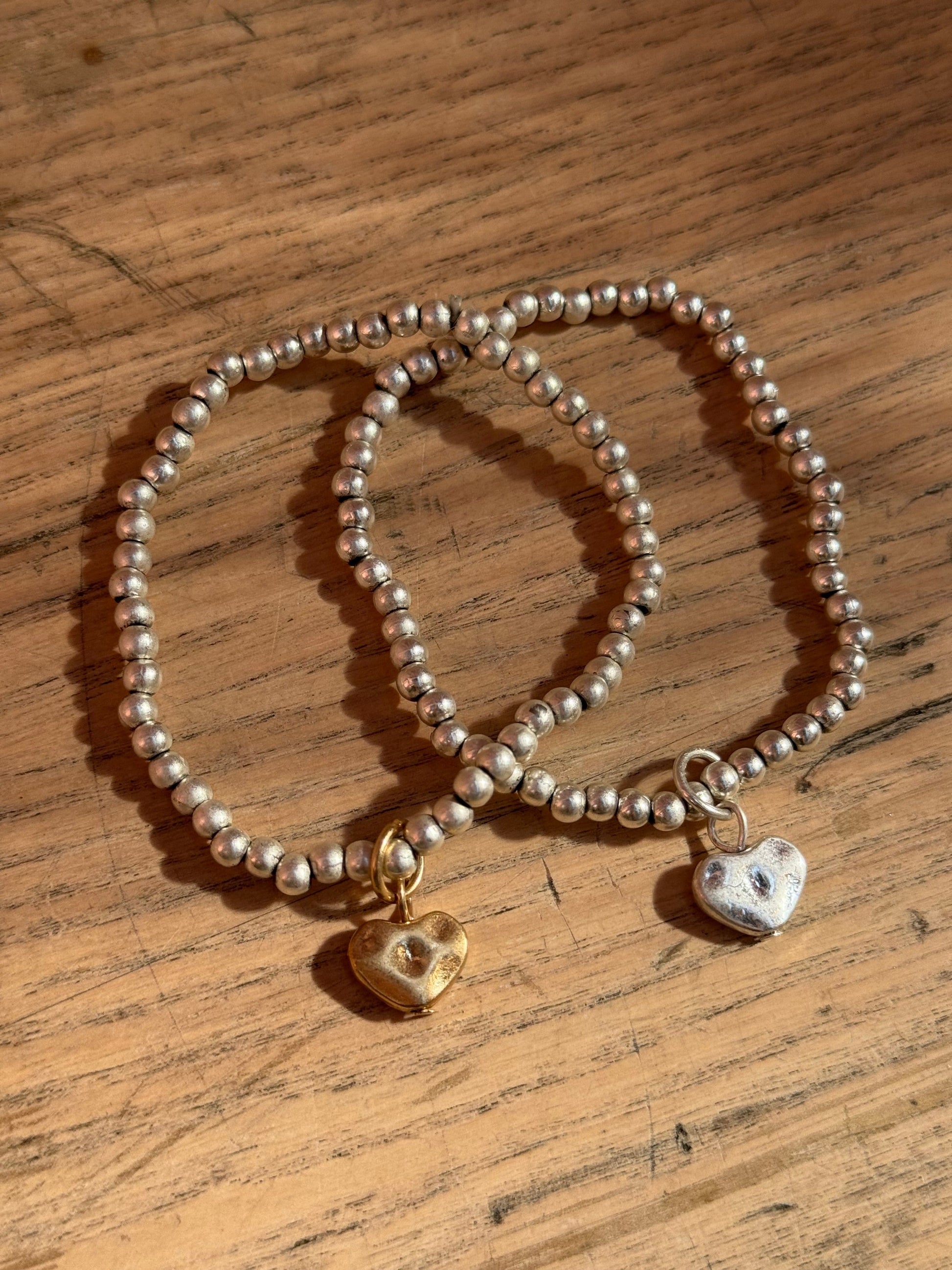 Set of two silver bracelets with heart charms in gold and silver
