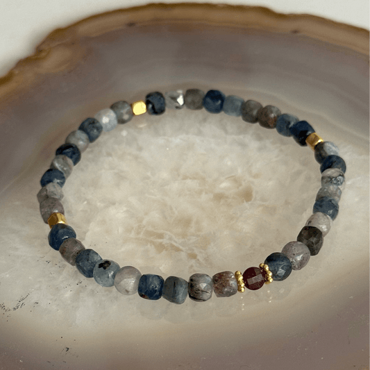 Beaded bracelet with blue, gray, and gold beads on a textured surface