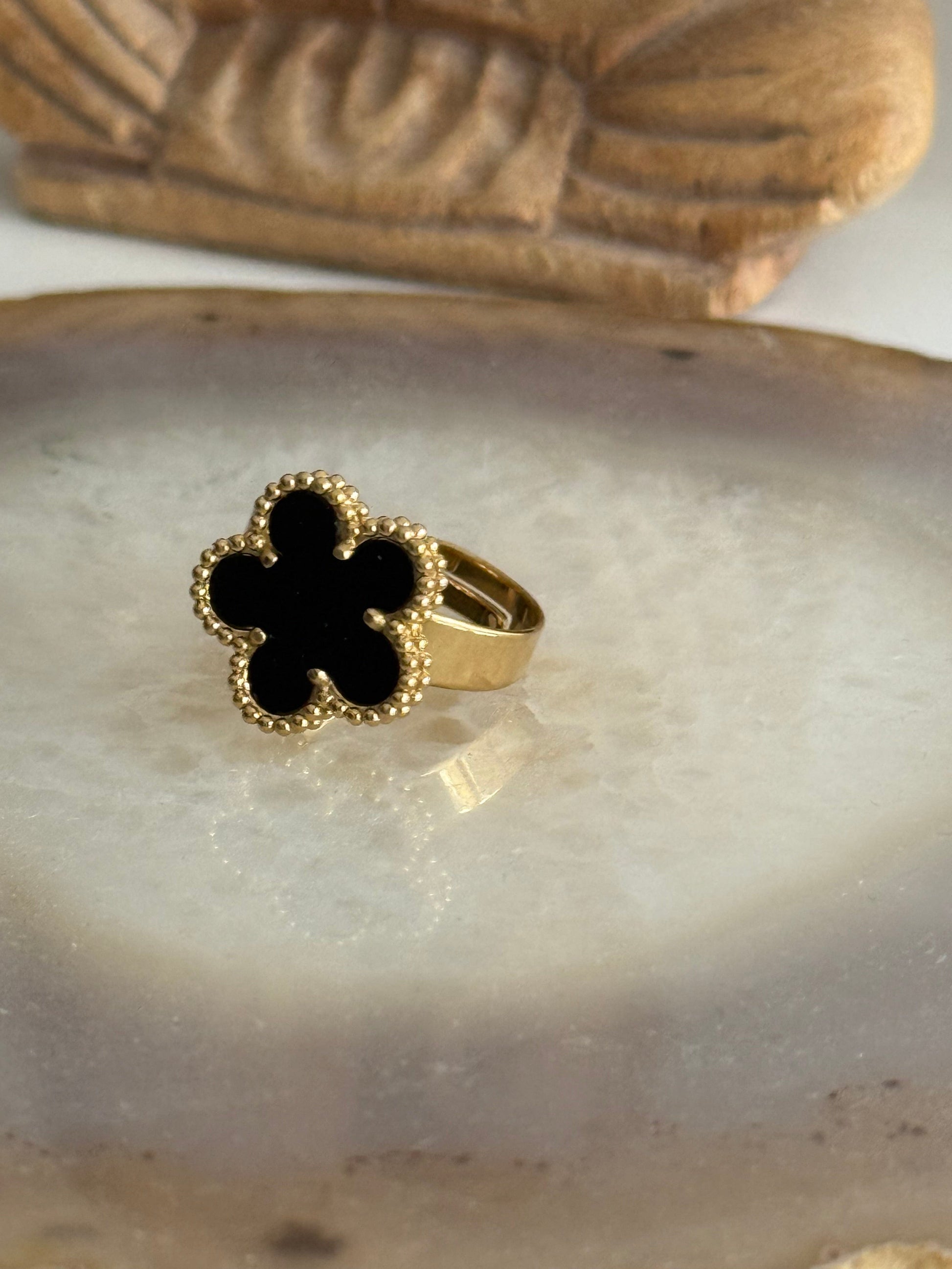 Gold ring with a black flower design on a stone surface