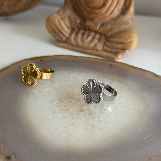 Gold and silver textured flower rings on a clear stone surface