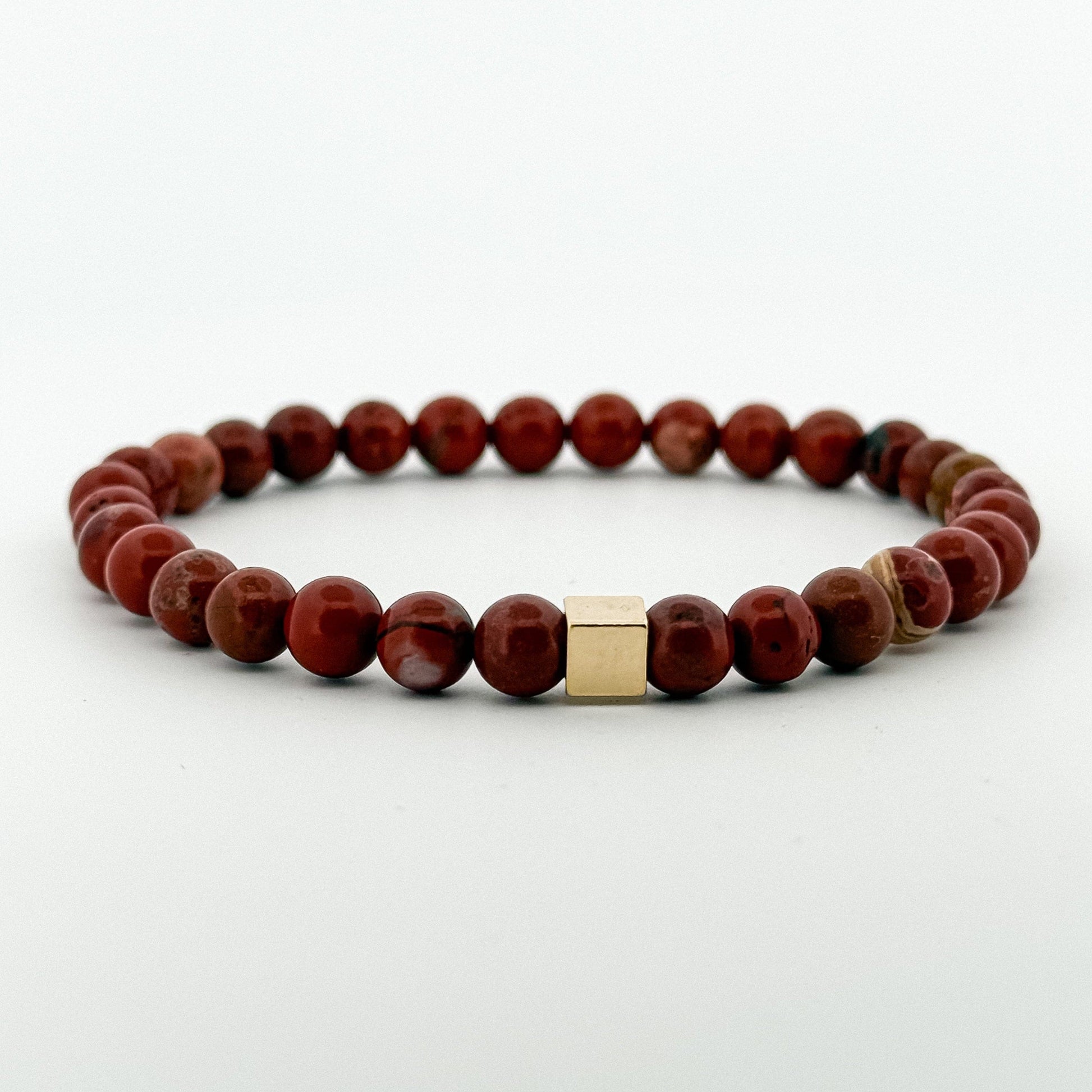 Bracelet with red jasper stones and a gold square charm bead