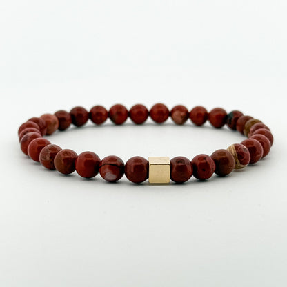 Bracelet with red jasper stones and a gold square charm bead