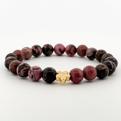 Bracelet with purple beads and a gold star-shaped charm on a white background