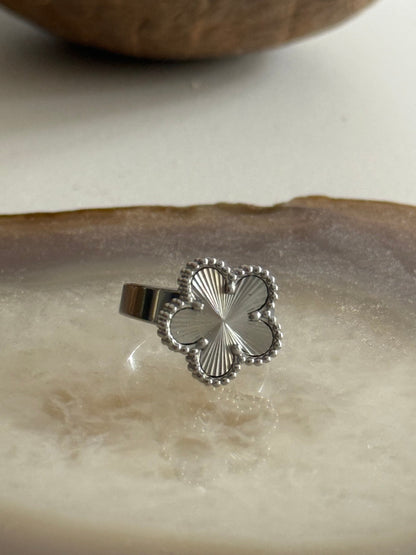 Silver four-leaf clover ring on a textured surface